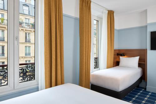 um quarto de hotel com duas camas e uma janela em Timhotel Paris du Gare du Nord em Paris