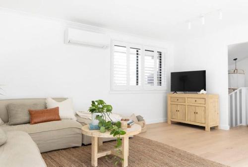 a white living room with a couch and a tv at Tingum in Lennox Head