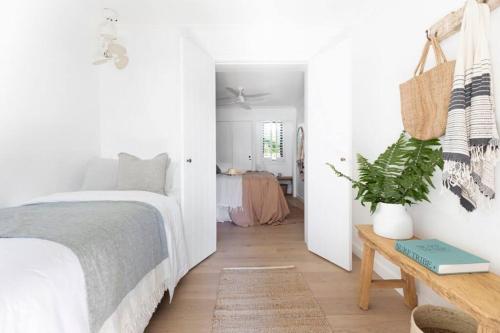 a white bedroom with a bed and a table at Tingum in Lennox Head