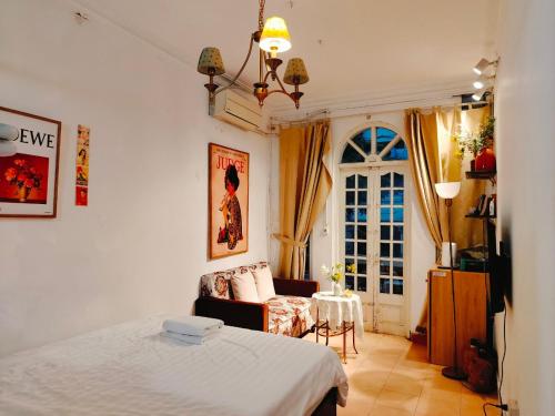 um quarto com uma cama, uma cadeira e uma janela em Cozy Fun Homestay 16 em Hanói
