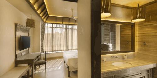 a bathroom with a sink and a mirror and a bedroom at Neonz Resort & Club in Anand
