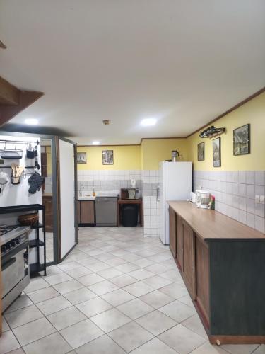 - une cuisine avec des murs jaunes et un réfrigérateur blanc dans l'établissement Gîte de la Peyrouse, à Saint-Jean-de-Vaux