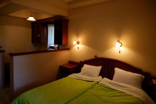 a bedroom with a bed with green sheets and white pillows at Archontiko tou Ziaka in Ipáti
