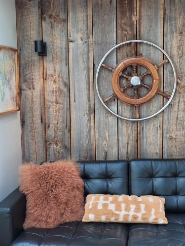 a leather couch against a wooden wall with a steering wheel at Tiny Villa de Haas met Infraroodsauna in Egmond aan Zee