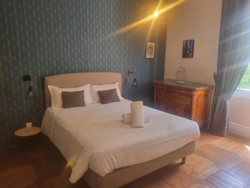 Un dormitorio con una gran cama blanca y una mesa en Le Manoir du Thouron, en Saint-Sulpice