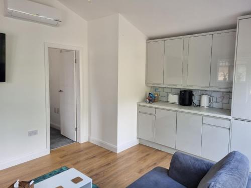 uma cozinha com armários brancos e um sofá azul em Arncliffe Annexe em Baildon