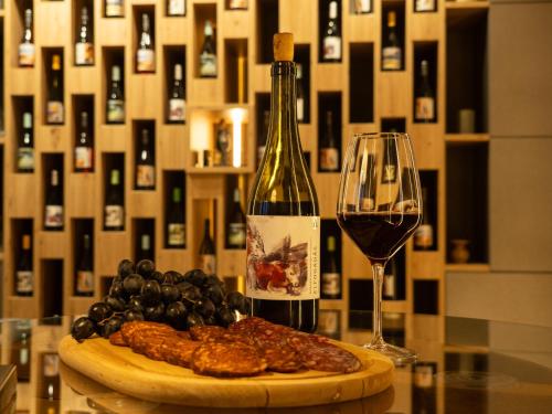 a bottle of wine and a plate of meat and grapes at DOG HILL Apartman in Dunabogdány