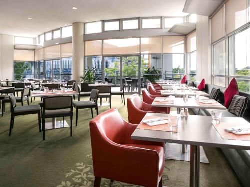 a dining room with tables and chairs and windows at Novotel Sydney Olympic Park in Sydney