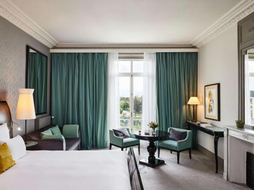 une chambre d'hôtel avec un lit, une table et des chaises dans l'établissement Le Grand Hotel de Cabourg - MGallery Hotel Collection, à Cabourg