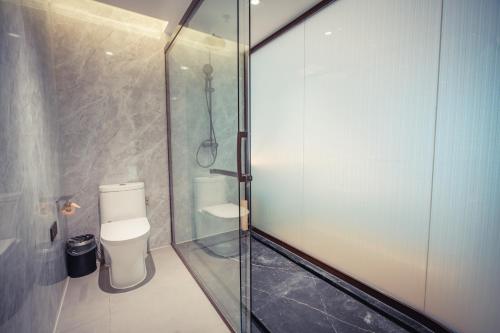 a bathroom with a glass shower with a toilet at Yun Qi Hotel in Baizhuang