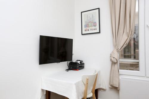 une table blanche avec une télévision murale dans l'établissement Studio Maine - Montparnasse Paris 14th, à Paris