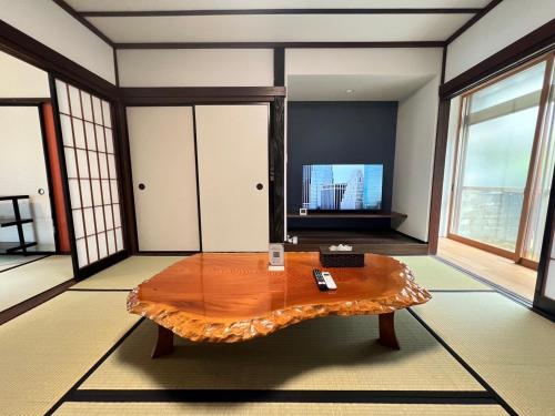 uma sala de estar com uma mesa de madeira e janelas em あざみ庵山中温泉 em Kaga