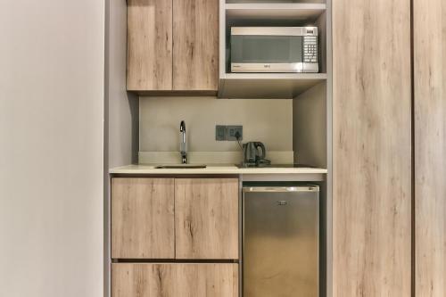 a small kitchen with wooden cabinets and a microwave at WINK Aparthotel One Thibault in Cape Town