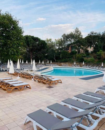 une piscine avec chaises longues et parasols dans l'établissement Apparemment Vue Mer - 6 personnes - Golfe de Saint Tropez, à Grimaud