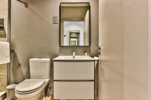 a bathroom with a toilet and a sink and a mirror at WINK Aparthotel One Thibault in Cape Town