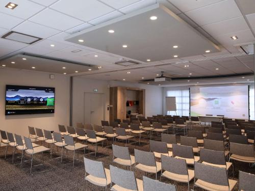 une chambre avec des rangées de chaises et un écran de projection dans l'établissement Ibis Styles Clermont-Ferrand République, à Clermont-Ferrand