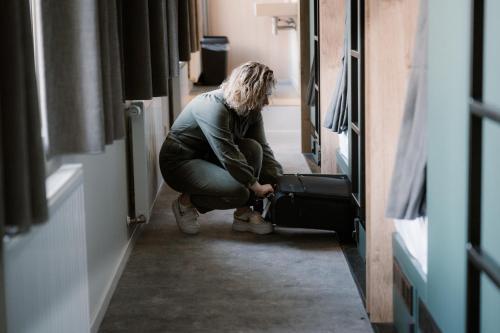 a woman kneeling down with a suitcase in a hallway at Stadsklooster Dordt Hotel&Hostel in Dordrecht