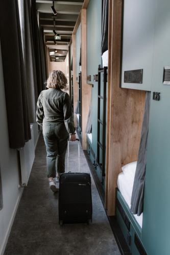 a woman walking down a hallway with a suitcase at Stadsklooster Dordt Hotel&Hostel in Dordrecht
