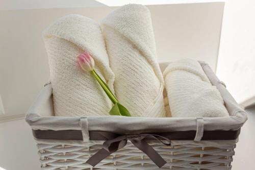 a pink flower sitting in a basket with towels at Apartma pri Jakobu in Postojna