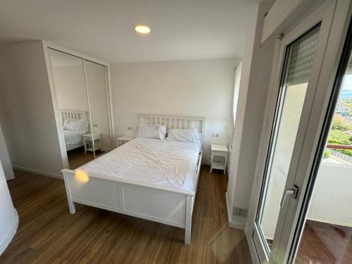 1 dormitorio con cama blanca y espejo en Duplex con Terraza en Mogro, en Mogro