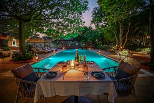 a table set for a meal in front of a swimming pool at LaRiSa Resort & Spa, Ashwem in Mandrem