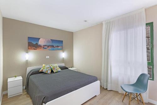 um quarto com uma cama e uma cadeira azul em Enjoy em Puerto Rico de Gran Canaria