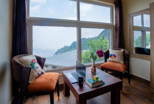 a living room with two chairs and a table and a window at The Social Stays Mussoorie formerly ArtBuzz in Mussoorie