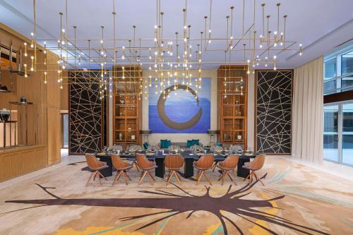 ein Esszimmer mit einem Tisch, Stühlen und einem Kronleuchter in der Unterkunft Andaz by Hyatt – Palm Jumeirah in Dubai