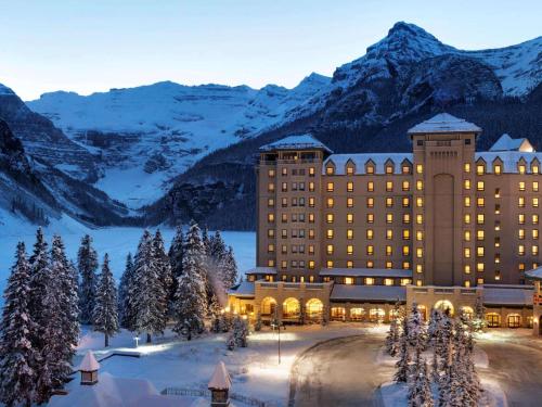 um hotel com montanhas cobertas de neve ao fundo em Fairmont Château Lake Louise em Lake Louise