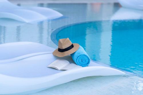 a hat and a book next to a swimming pool at Hyatt Centric Jumeirah Dubai in Dubai