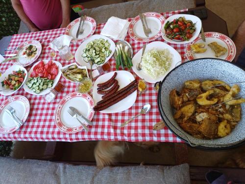 una mesa llena de comida en un paño de mesa blanco y rojo en Apartman i Krčma u Planini, en Bojnik