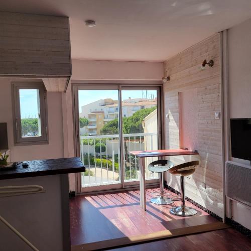 une cuisine avec une table et deux tabourets devant une fenêtre dans l'établissement Studio-2 Personnes-Résidence Le Pharo, Vue Piscine Port, au Cap d'Agde