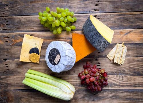 a bunch of cheese and vegetables on a wooden table at Farlam Hall Hotel & Restaurant in Brampton