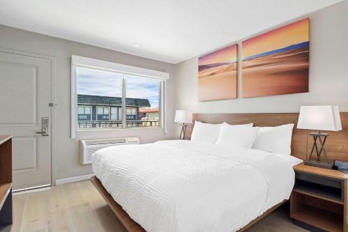 um quarto com uma grande cama branca e uma janela em Clarion Pointe Ridgecrest near China Lake Naval Station em Ridgecrest
