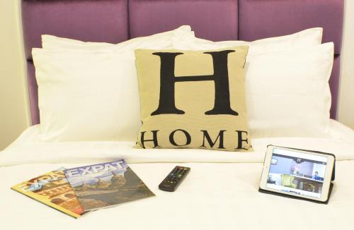 a bed with a book a remote control and a tablet at H Boutique Hotel Sri Petaling in Kuala Lumpur