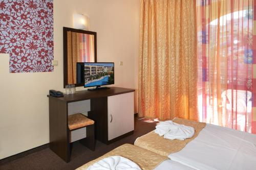 a hotel room with a bed and a television on a desk at Yavor Palace Hotel - All Inclusive in Sunny Beach