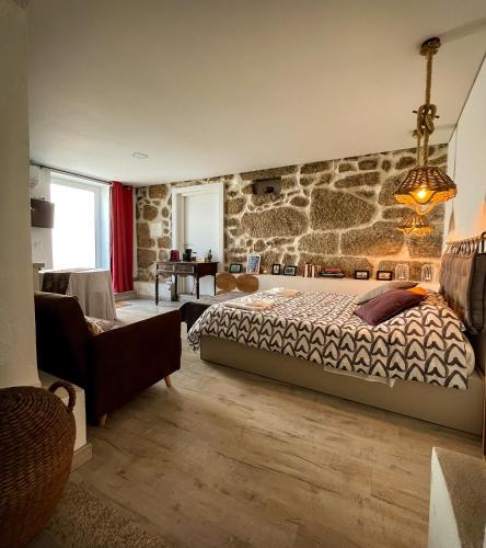 1 dormitorio con cama y pared de piedra en Casa da Fonte Grande, en Belmonte