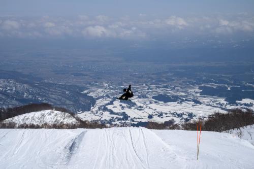 a person riding a snowboard down a snow covered slope at Lotte Arai Resort in Myoko