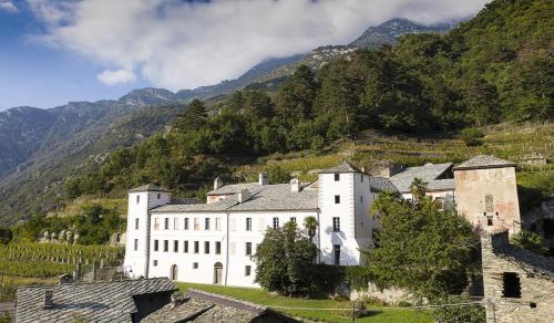 a large white building in front of a mountain at La torre in Arnad