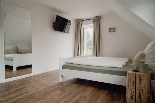 a white bedroom with a bed and a mirror at Traumfabrik Eifel mit Sauna & Whirlpool in Monschau