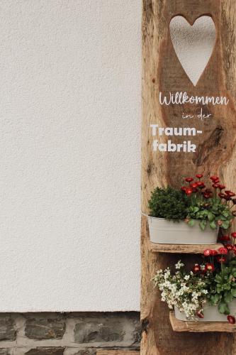 a wall with two potted plants and a heart sign at Traumfabrik Eifel mit Sauna & Whirlpool in Monschau