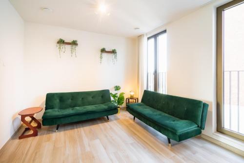 a living room with two green couches and a window at Opera Apartments in the Center of Antwerp in Antwerp