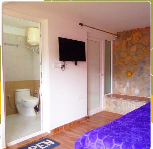a bedroom with a toilet and a tv on a wall at The Himalayan Streets home stay in Mukteswar