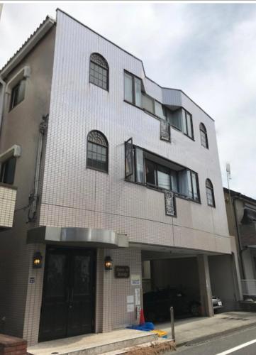 a tall white building with windows on a street at メゾンドリバージュ201 in Tokyo
