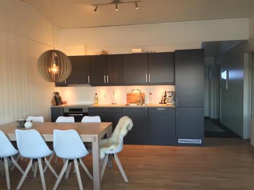 a kitchen with a table and some white chairs at Voss Resort self-service apartments in Skulestadmo
