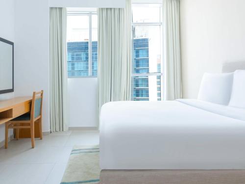a bedroom with a bed and a desk and a window at Grand Heights Dubai Hotel Apartments in Dubai