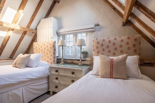 2 Betten in einem Schlafzimmer im Dachgeschoss mit Holzbalken in der Unterkunft The Beekeepers Cottage in Barney