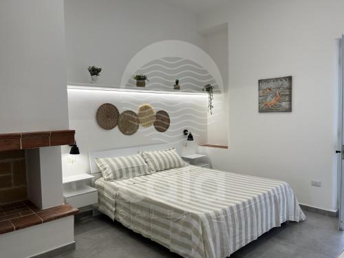 a white bedroom with a bed with a striped comforter at Roma n 3 in Torre Lapillo