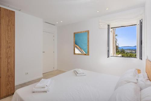a white bedroom with a bed and a window at Villa Bonjour in El Port