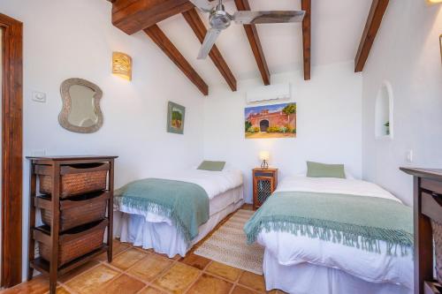 two beds in a room with white walls and wooden ceilings at Finca Can Puput in Campanet
